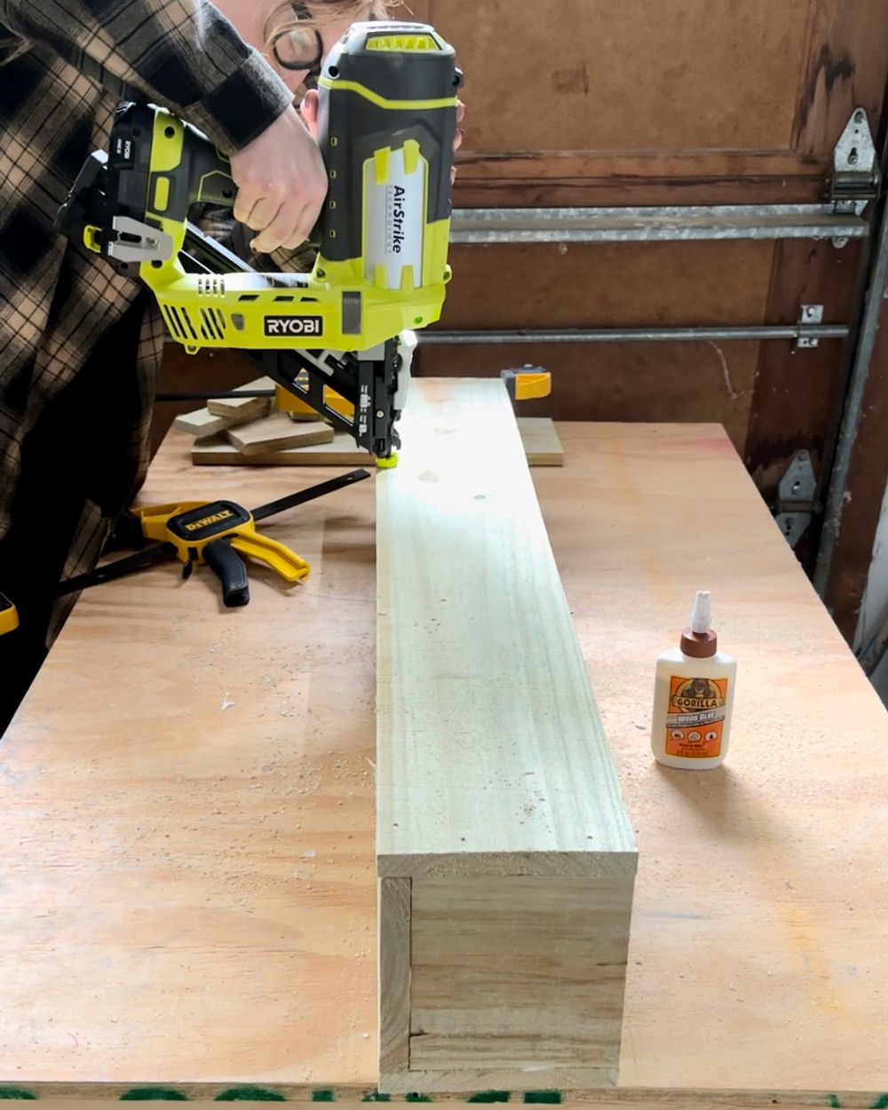 A woman using a Ryobi nailer to make a wall mounted planter. A woman using a Ryobi nailer to make a wall mounted planter.