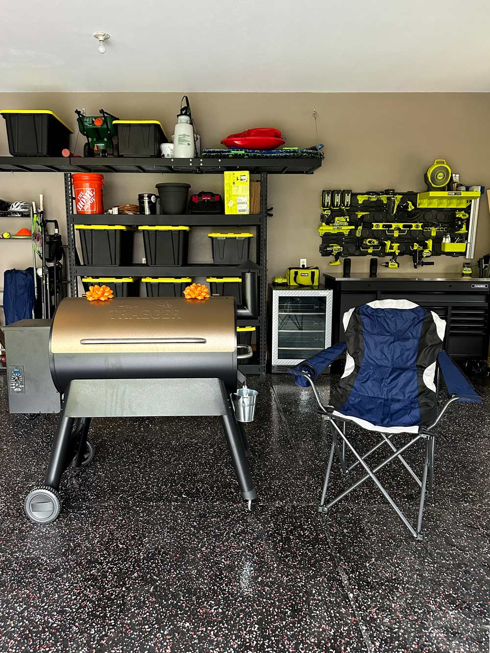 A clean garage with storage shelving, containers, a workbench equipped with tools, and a grill with bows.
