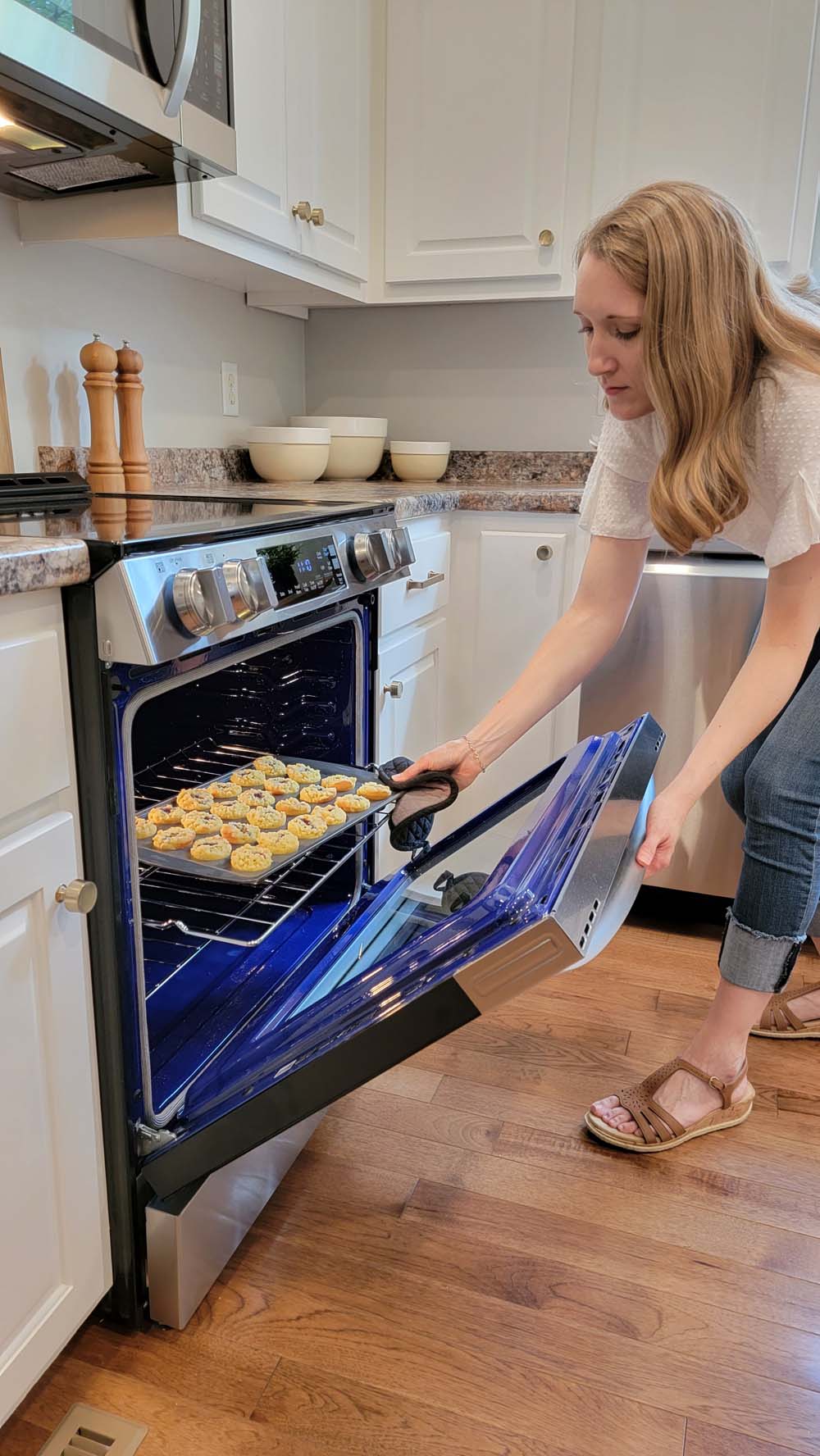 Cookies being taken out of the oven by a woman.