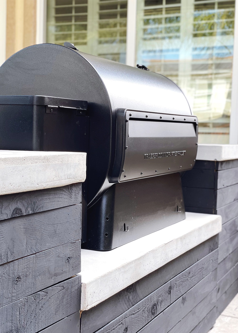 Corner angle of a black Traeger Grill sitting on a custom black and white countertop
