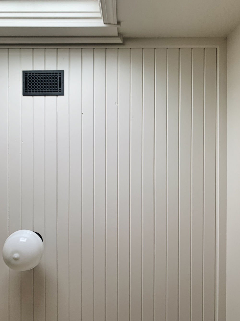 The bedroom ceiling with white light and a small black vent.