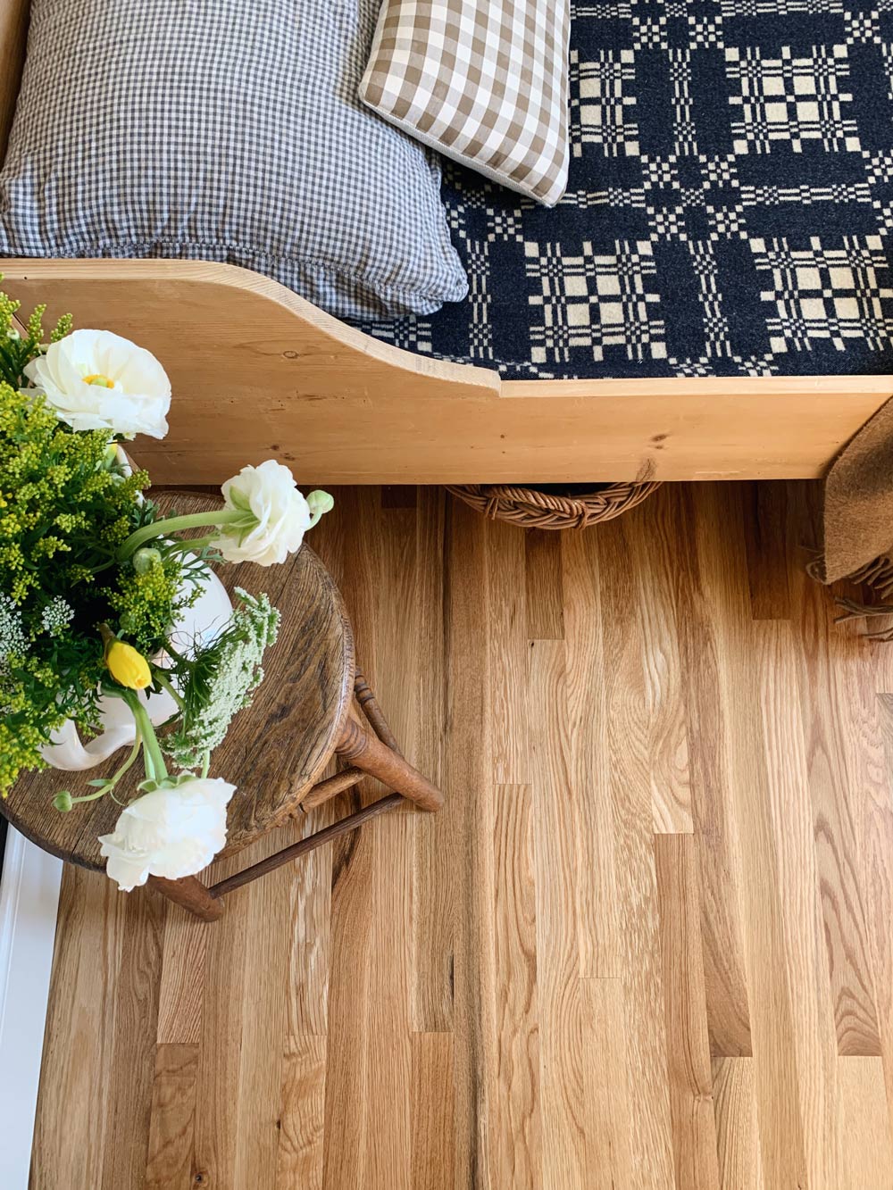The corner of an empty bedroom, with wooden floors and white walls.