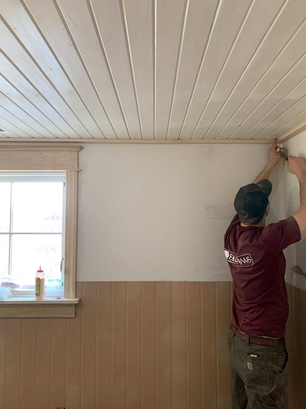 A man installing wooden ceiling panels.