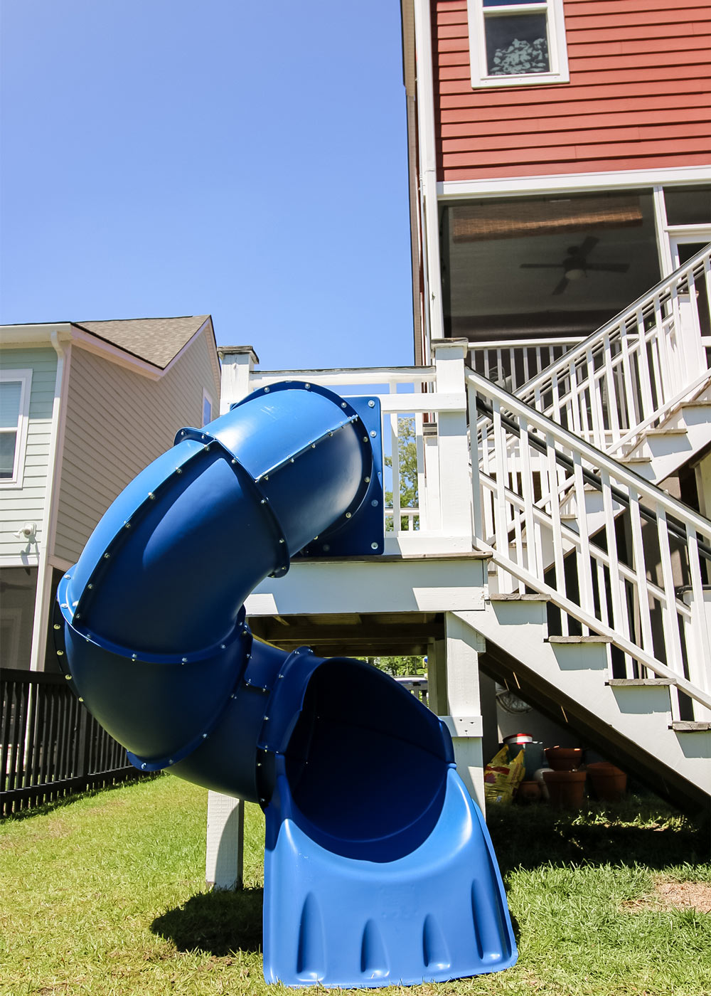 a blue slide connected to a deck with white stairs