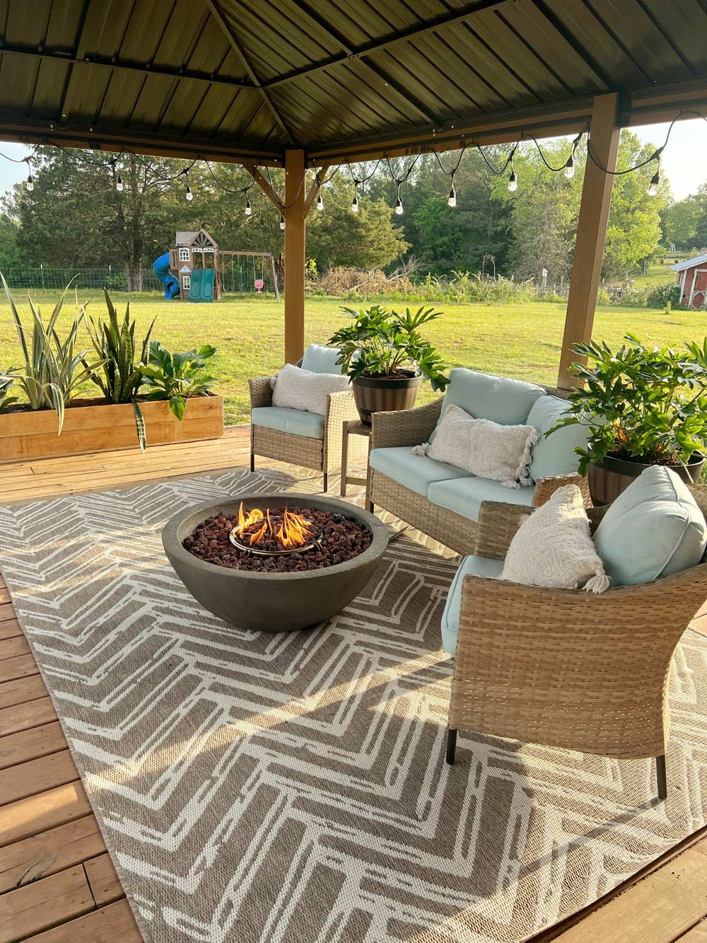 A decorated patio area under a gazebo, with a playground set in the background. A decorated patio area under a gazebo, with a playground set in the background.