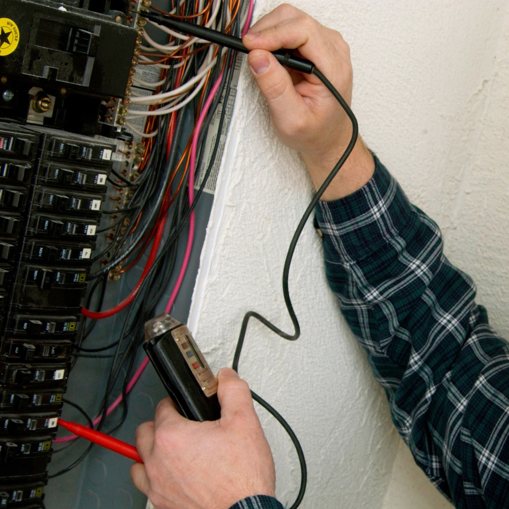 An electrician checks a breaker box.