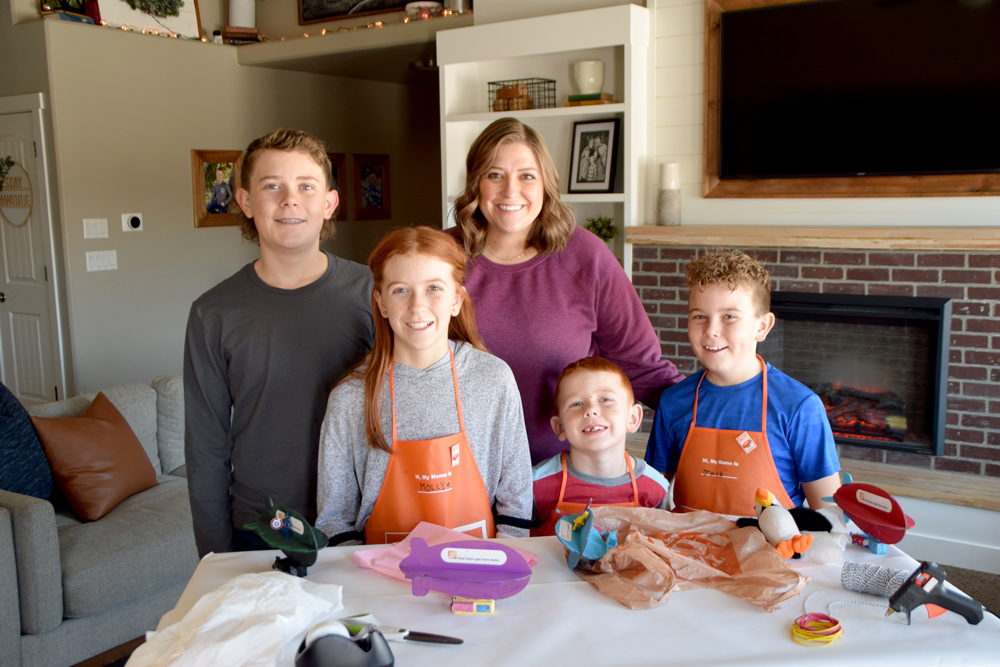 mom and kids gathered around a table with orange aprons