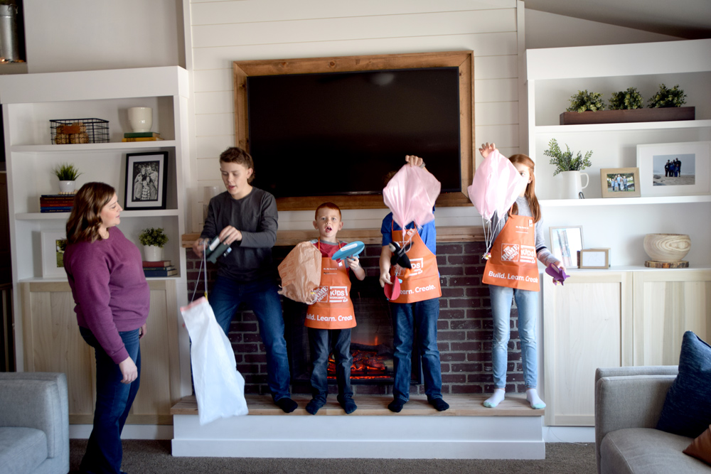 Kids testing parachutes with airships on fireplace step