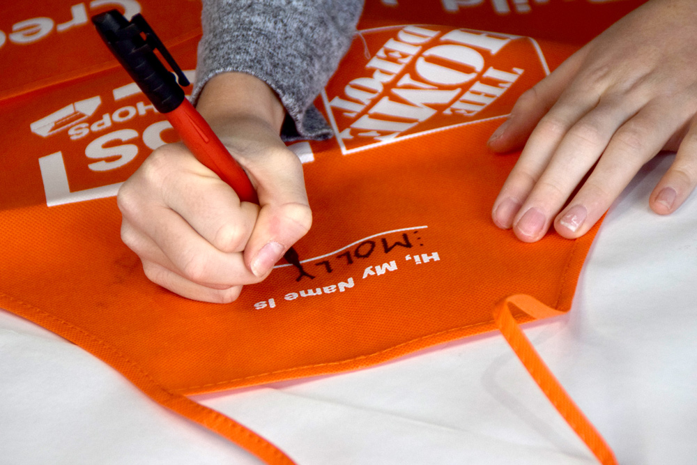 hands writing Molly on apron