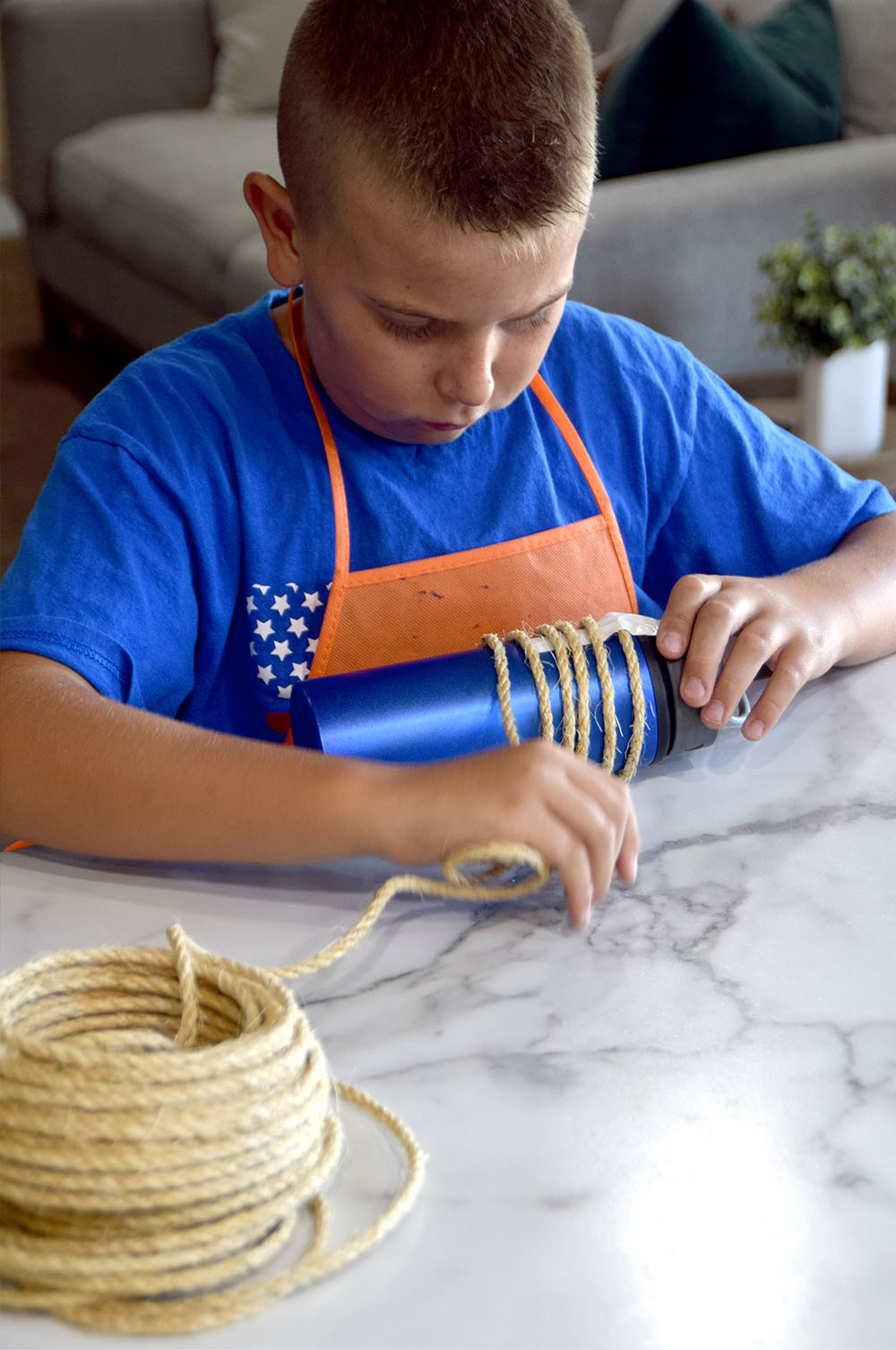 A child wrapping rope around a bottle to create bends in the rope.