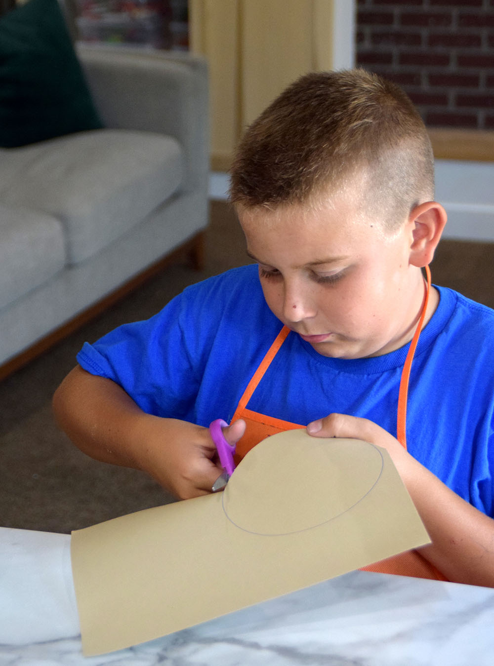 A child using safety scissors to cut out a circle from the sheet of cardstock.