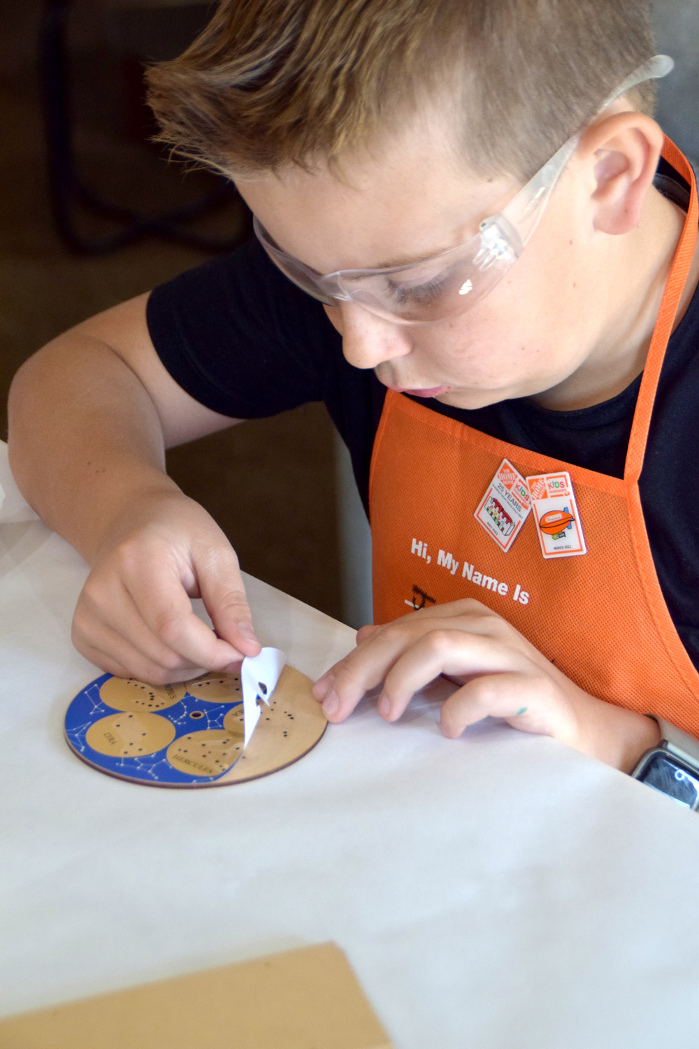 Boy placing a constellation sticker on top of a disk.