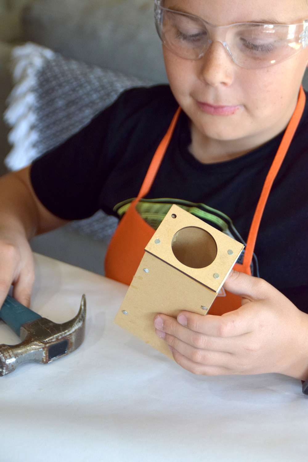 Boy holding his in-progress viewer in his right hand, and hammer in the left.