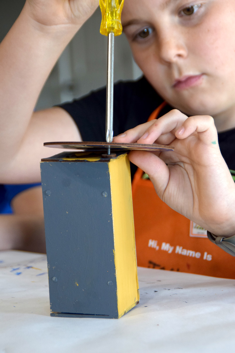 Boy using a screw and screwdriver to attach a top piece.