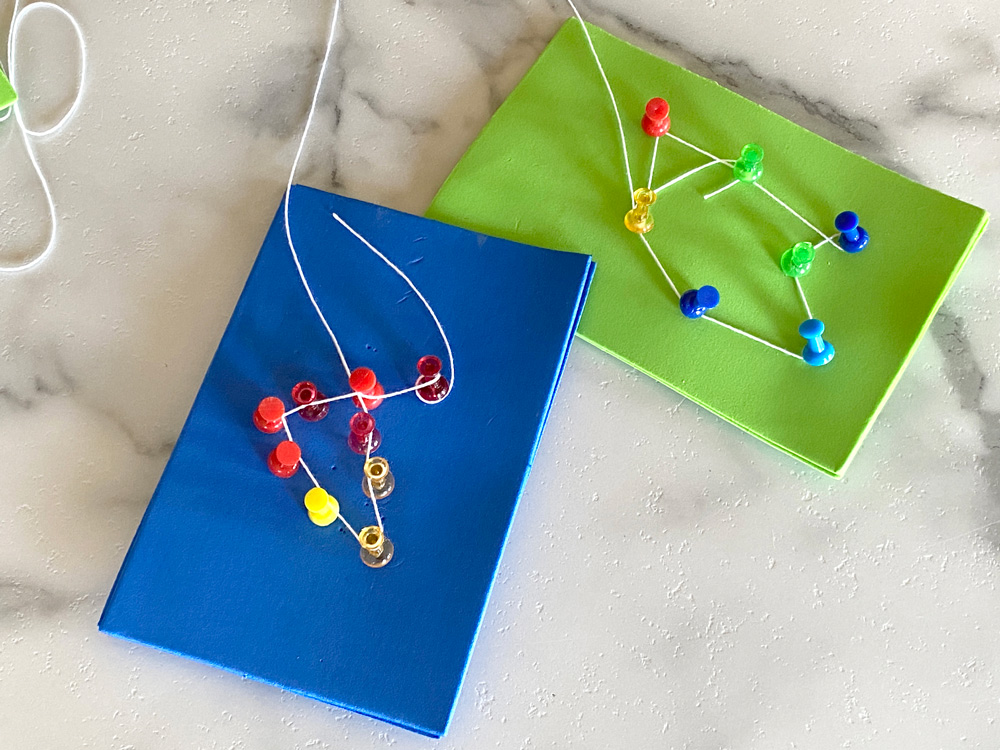 Green and blue craft foam with thumbtacks and strings creating constellation shapes.