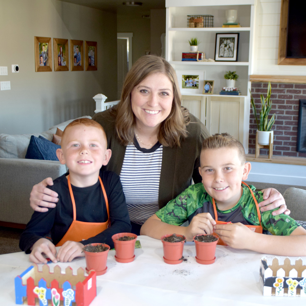 Two boys and a mom with planter supplies set out in front of them