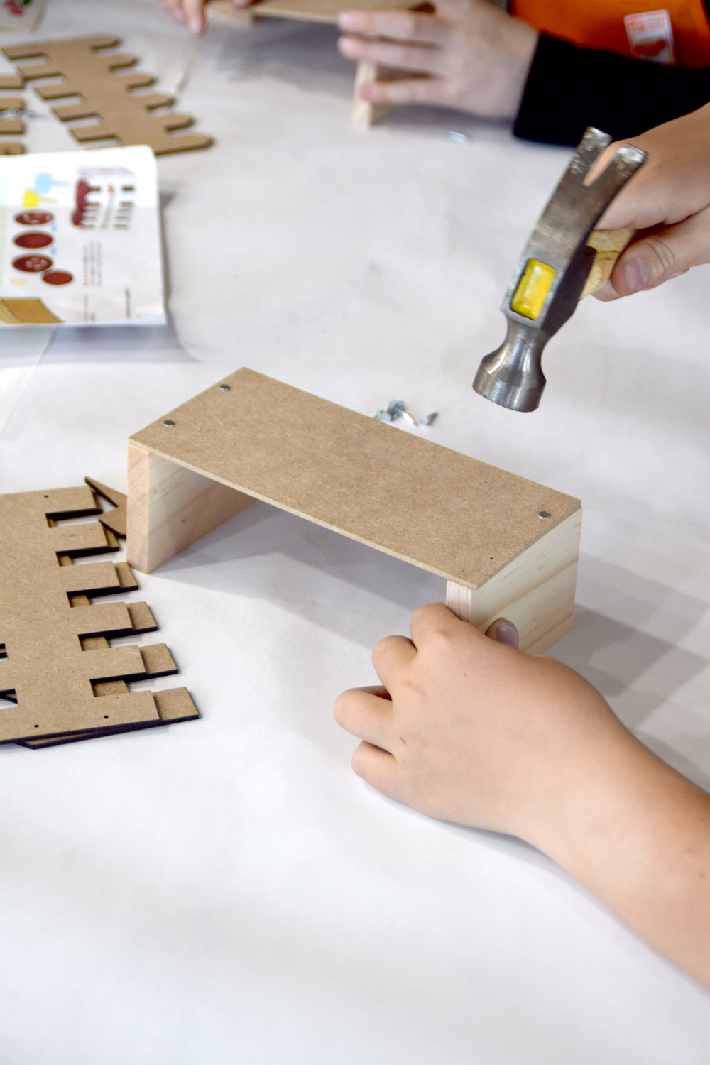 A child’s hands using a hammer to nail together Picket Fence Planter pieces.