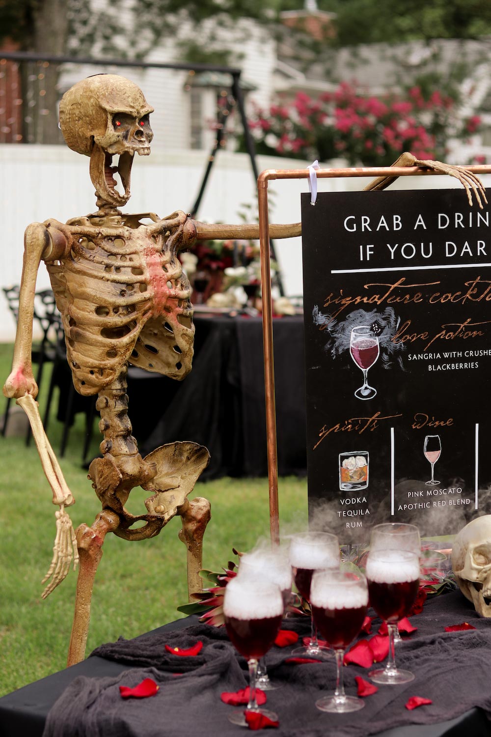 A skeleton with glowing red eyes standing in front of a table with foggy drinks.