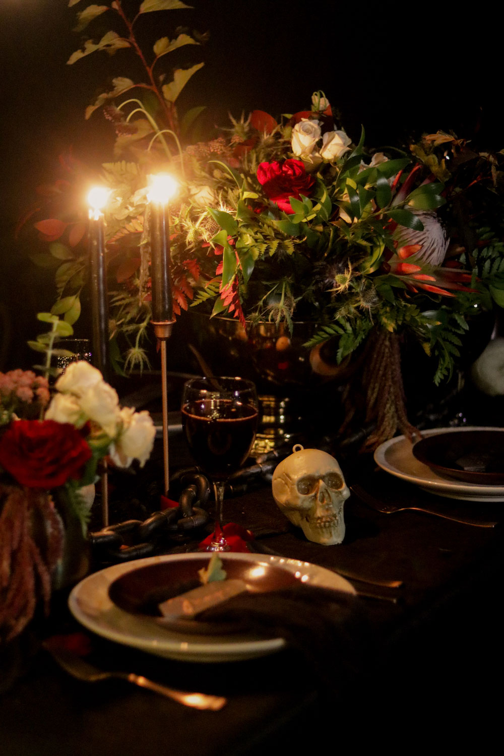 A table decorated with black lit candles and skeleton heads for Halloween.