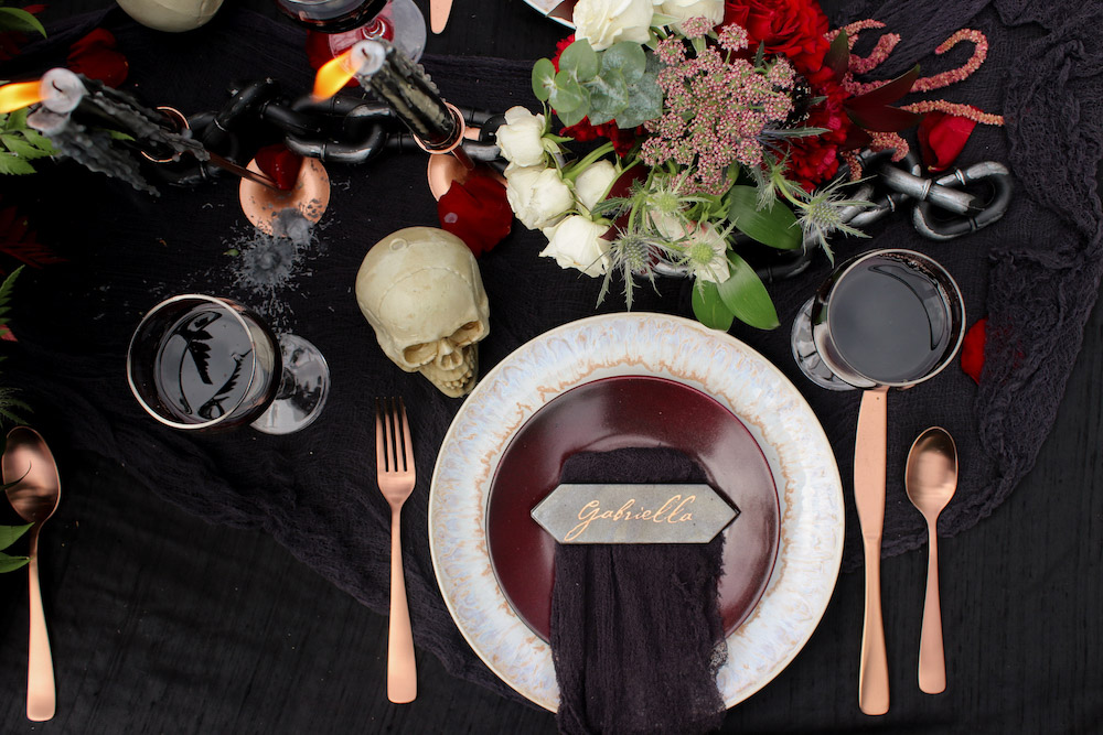 A table decorated with copper flatware, black linens, and personalized name cards.