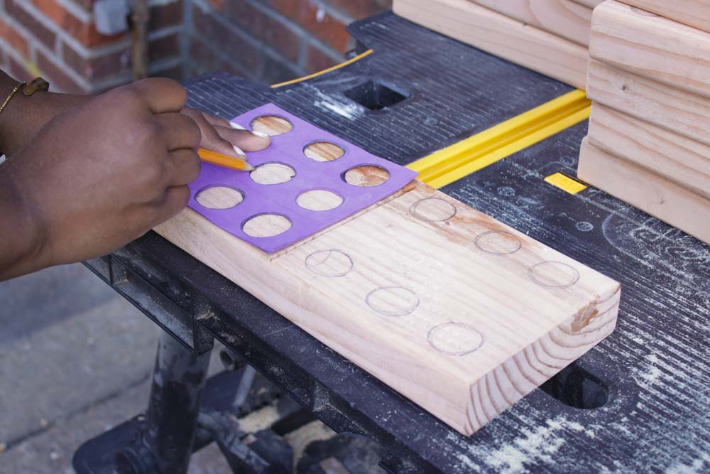 Women hand drawing even circles in dominoe format on large wooden block. Women hand drawing even circles in dominoe format on large wooden block.