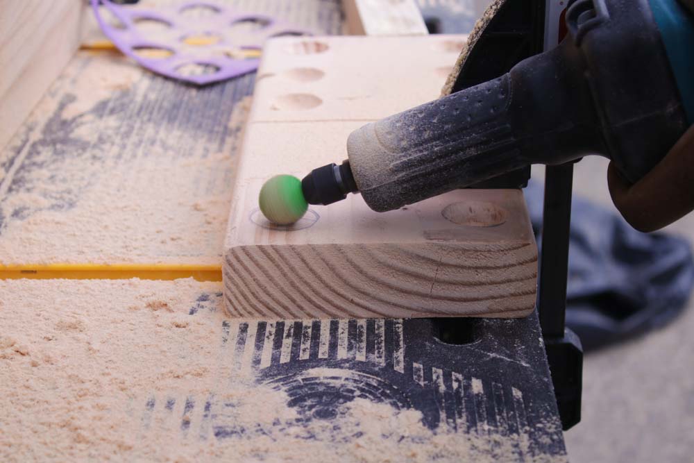 A person hand using burr grinder to carve shallow circles into large wooden block. A person hand using burr grinder to carve shallow circles into large wooden block.