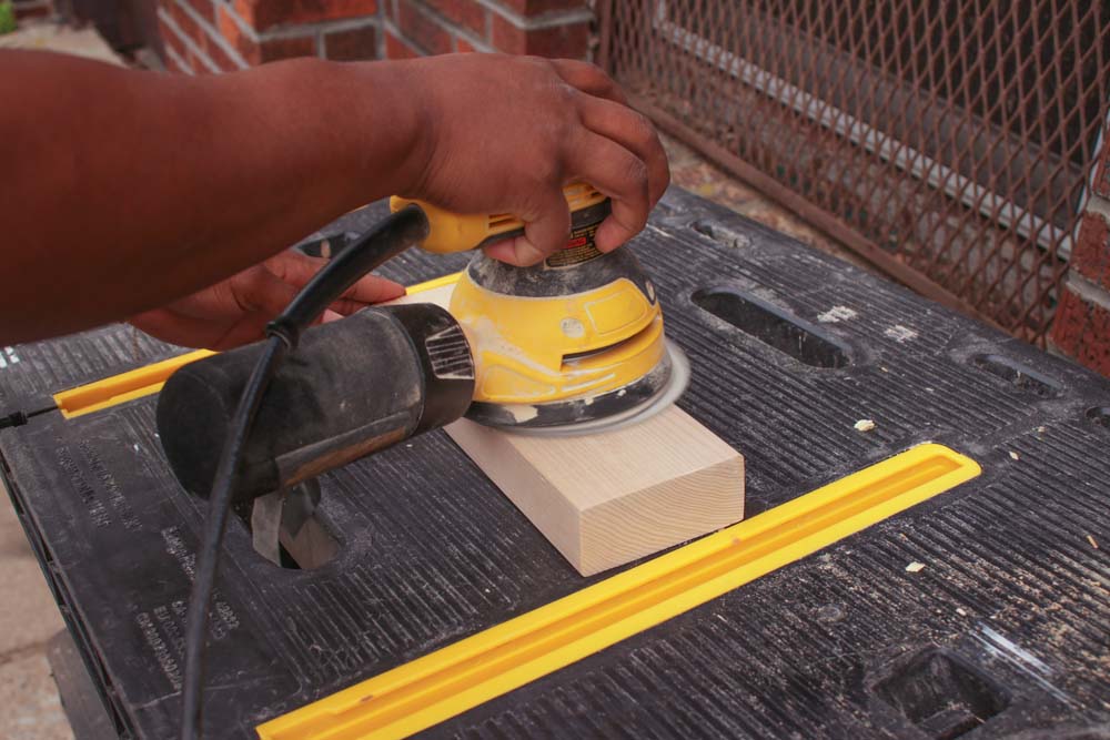 A person hand sanding down light wooden block. A person hand sanding down light wooden block.