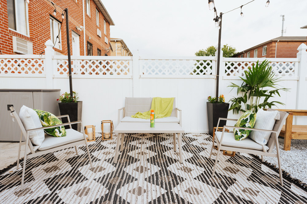 Rooftop space with patio seating, a patterned rug, and a white fence in the back.