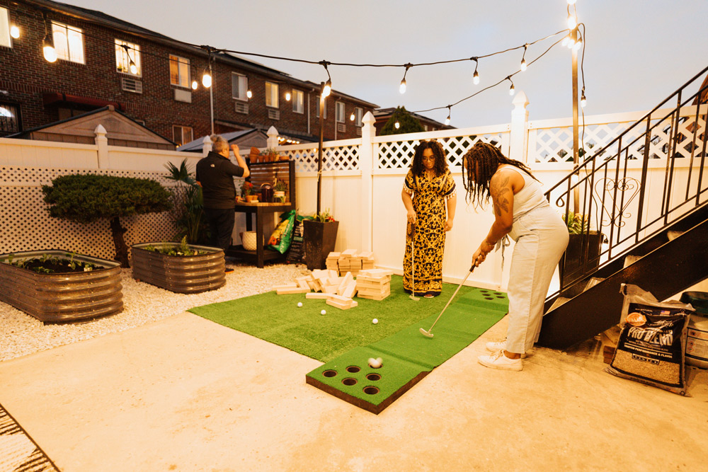 Two women playing a game of putting green on a rooftop patio.