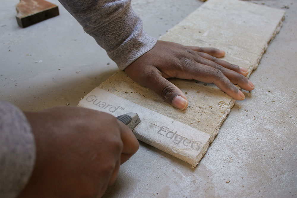 A woman using a boxcutter to cut into a wood board. A woman using a boxcutter to cut into a wood board.