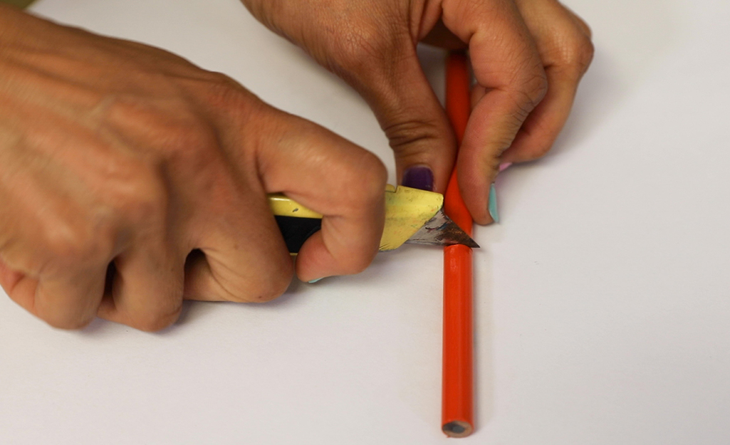 A person cutting a piece of a pencil.