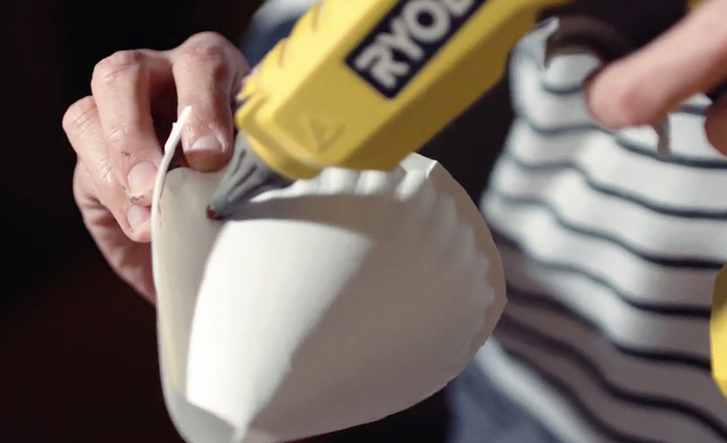 A person gluing a paper cone to make a castle turret. A person gluing a paper cone to make a castle turret.