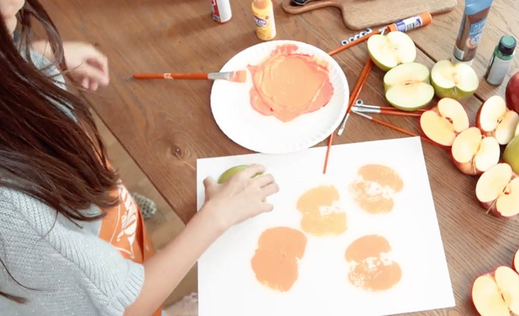 A person pressing an apple stamp to paper. A person pressing an apple stamp to paper.