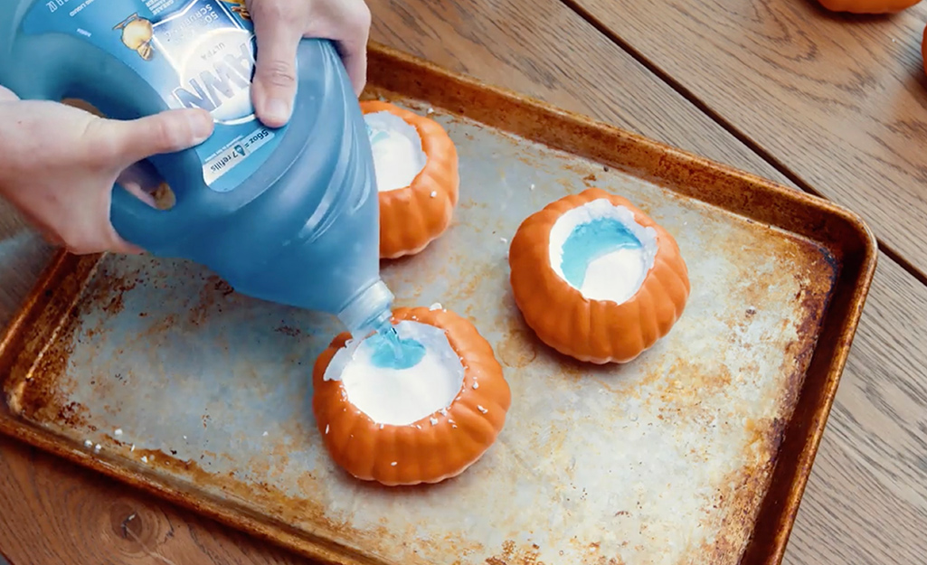 A person adding "lava" ingredients to a pumpkin shell. A person adding "lava" ingredients to a pumpkin shell.