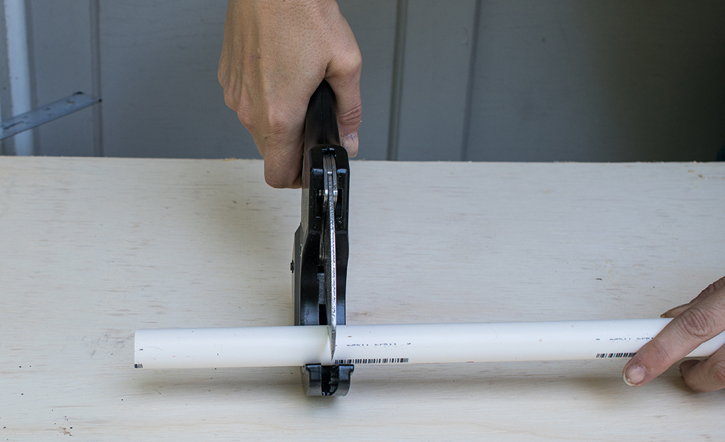 A person cutting pipe with a PVC cutter.