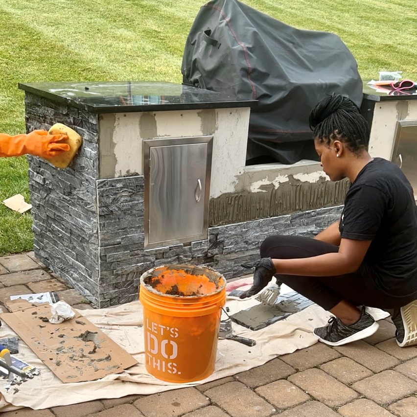 woman placing ledger stone on the outside of the grill