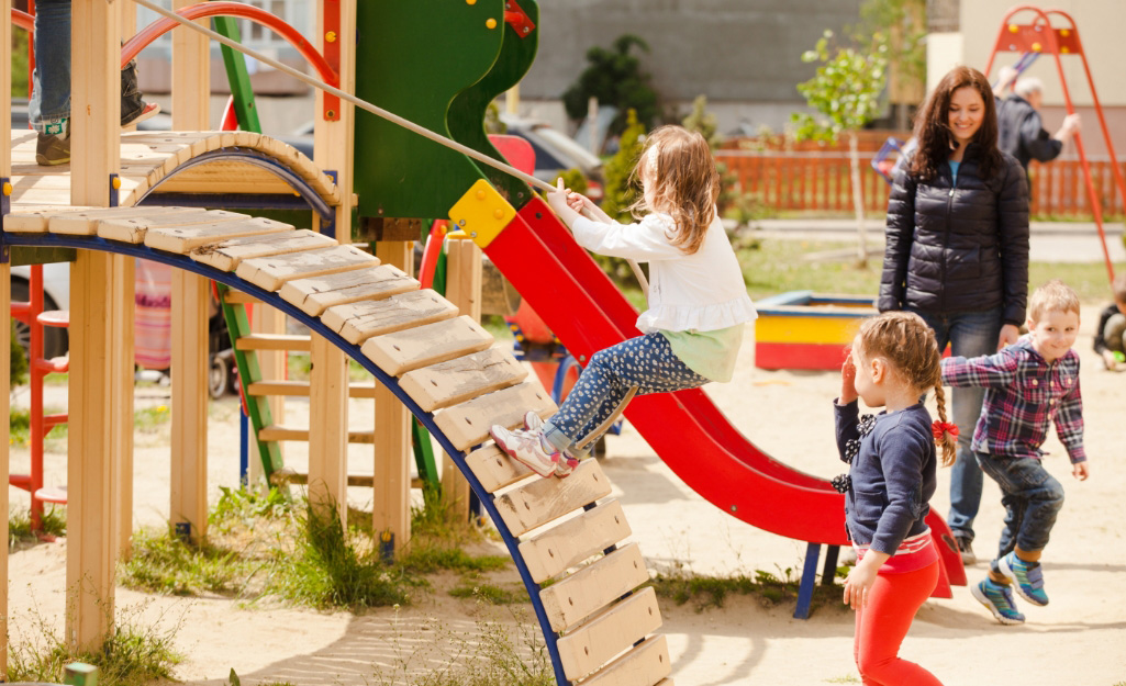 Children climb on a playset with a rope.