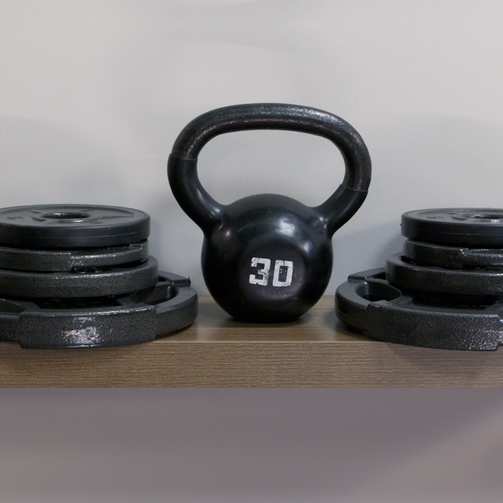 Kettlebell and weights sitting on top of a floating shelf.