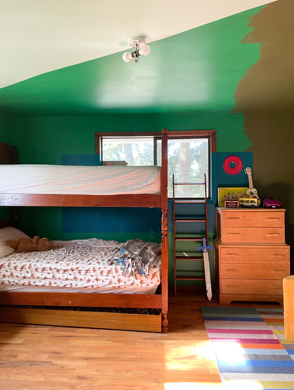 Bunk beds and a dresser with a ceiling painted green.