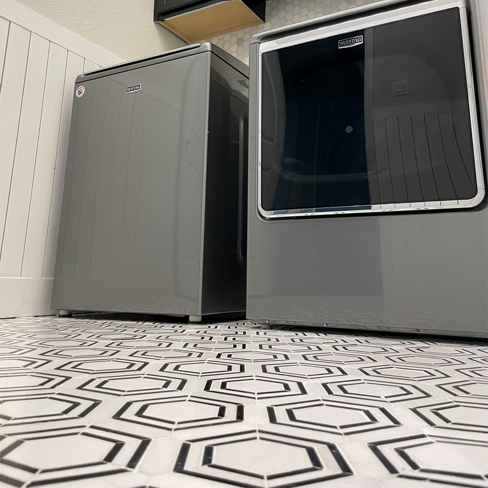 Up close photo of floor tiling, washing machine, and dryer.  