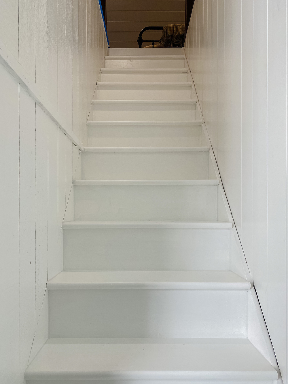 Staircase with fresh coat of white paint with white painted walls.