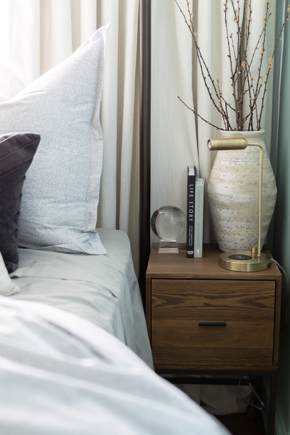 A glass globe and brass table lamp decorate the top of a wooden nightstand. A glass globe and brass table lamp decorate the top of a wooden nightstand.