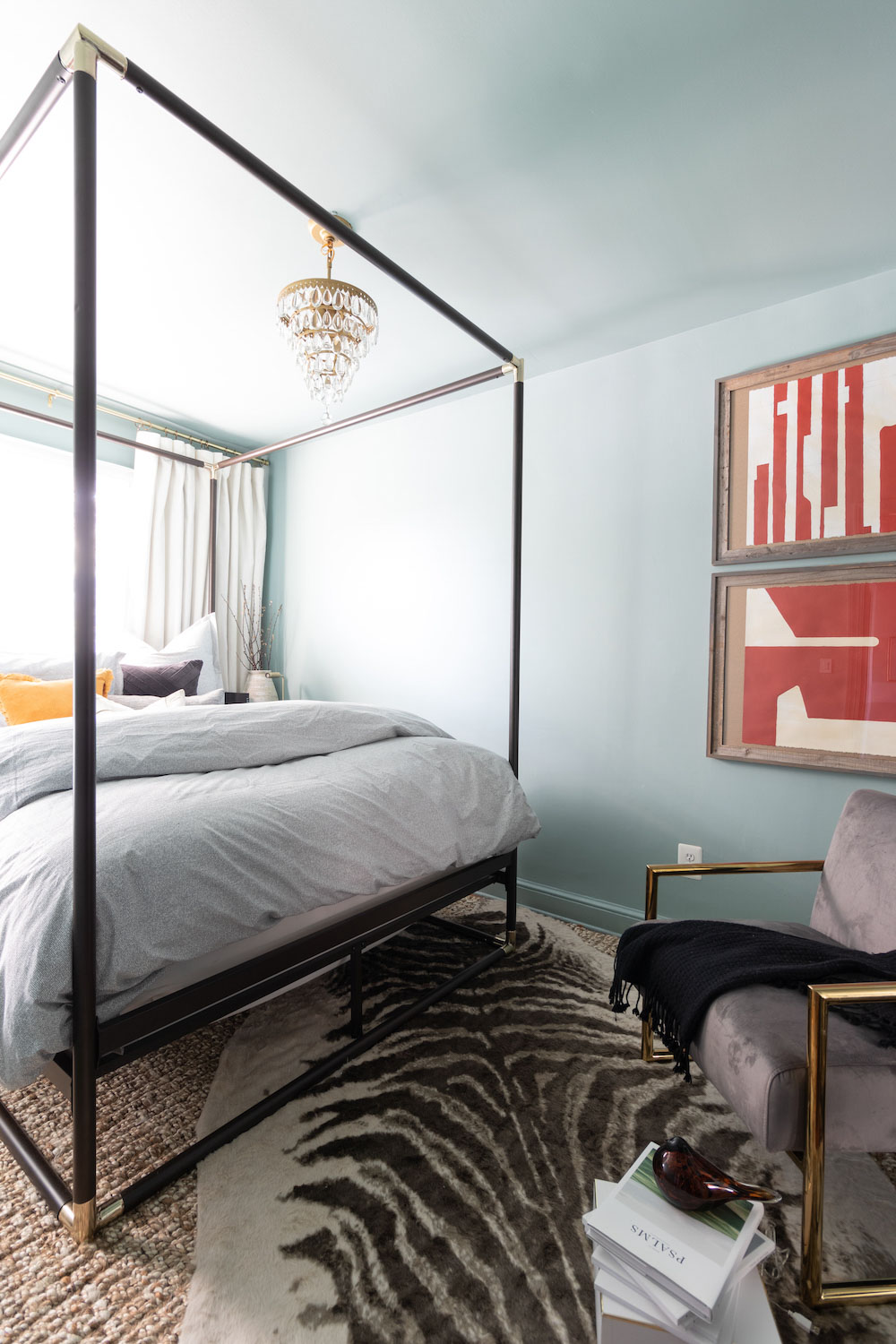 A bedroom with light blue walls and a black canopy bed. A bedroom with light blue walls and a black canopy bed.