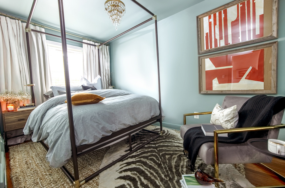 A bedroom featuring a black canopy bed, seating area, and a chandelier. A bedroom featuring a black canopy bed, seating area, and a chandelier.