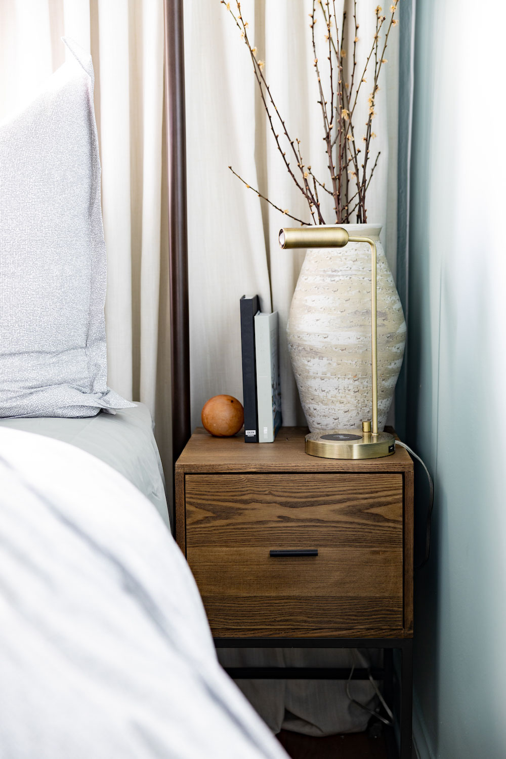 A wooden side table decorated with a large vase and brass table lamp. A wooden side table decorated with a large vase and brass table lamp.