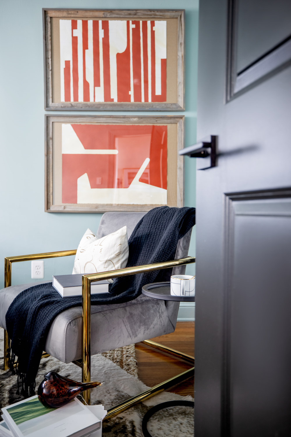 A door opening into a room decorated with red abstract art and a velvet accent chair. A door opening into a room decorated with red abstract art and a velvet accent chair.