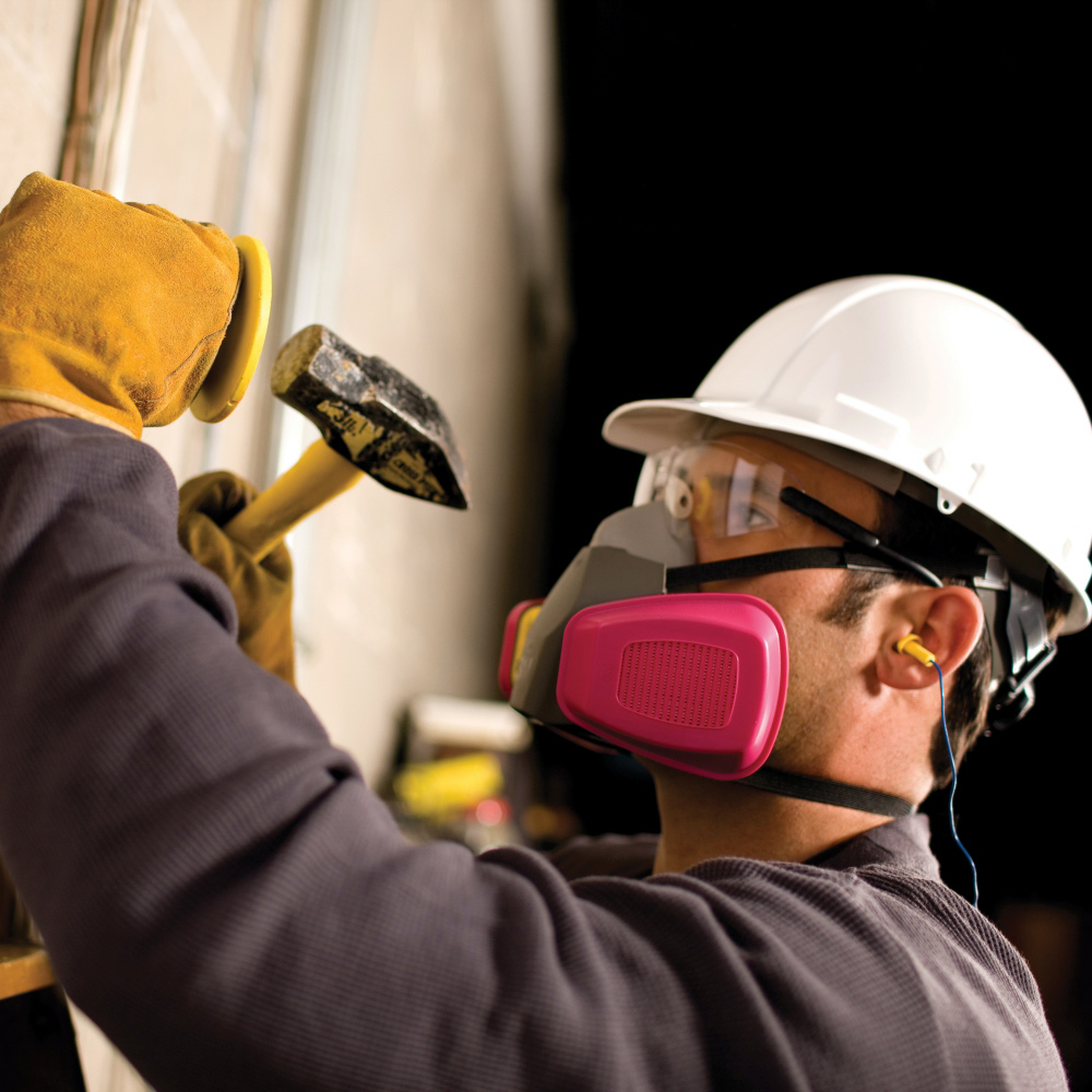 A worker wears a respirator and a hard hat.