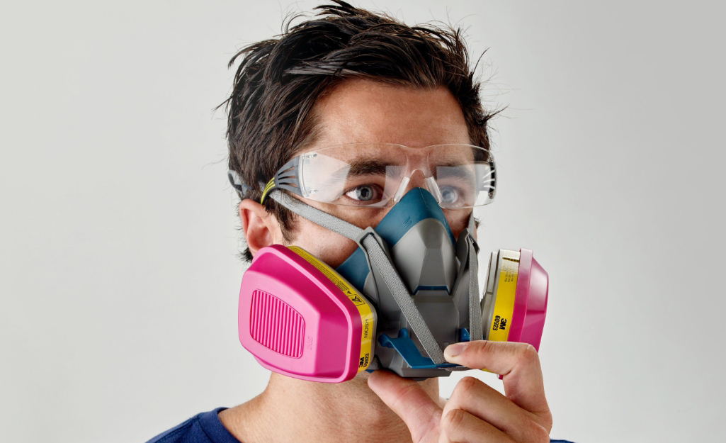 A worker wears a respirator.
