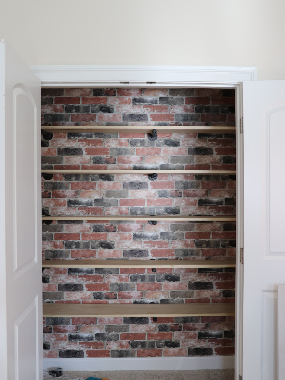 An updated closet with brick peel-and-stick wallpaper and open shelving. An updated closet with brick peel-and-stick wallpaper and open shelving.