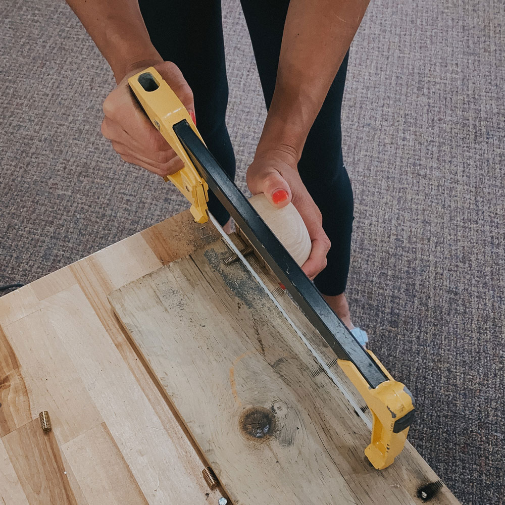 A person using a hand saw to cute down the screws. A person using a hand saw to cute down the screws.